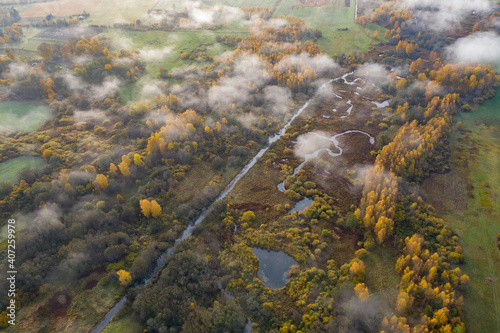Aerial view of golden yellow autumn forest and water lakes wetland. Morning above clouds and fog