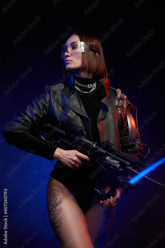 Fantasy portrait of a martial woman dressed in stylish black clothing and holding futuristic rifle. Female mercenary in cyberpunk style posing in dark and colourful background.