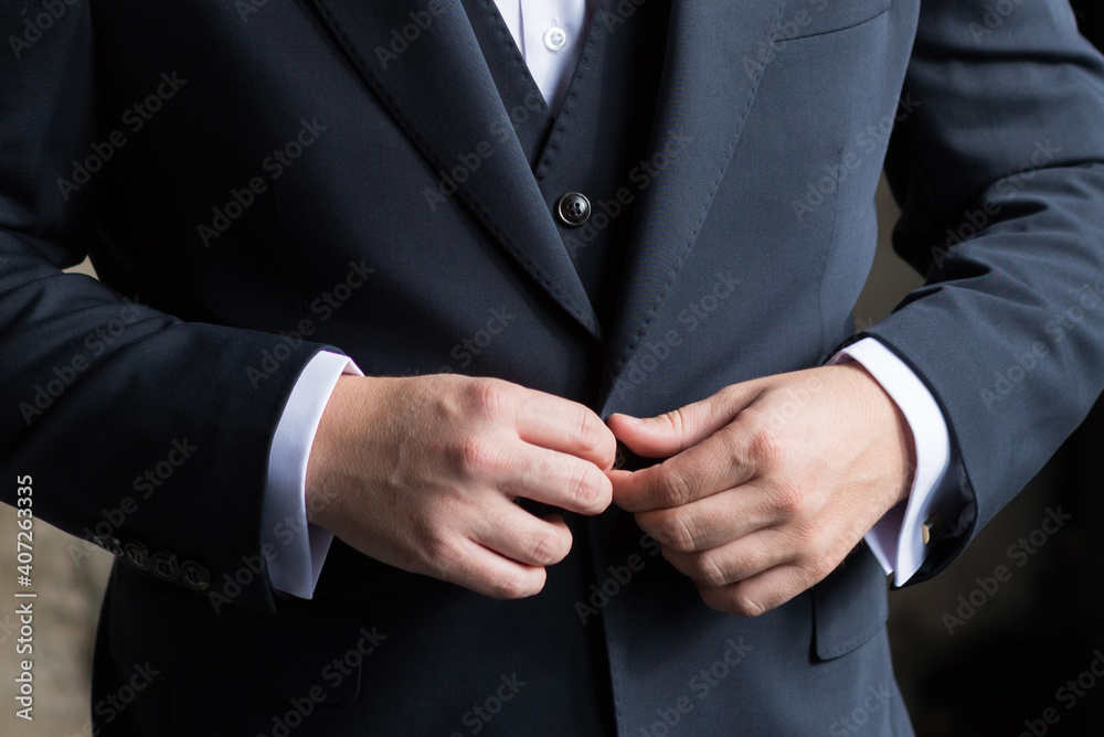 A man buttoning a business suit close-up