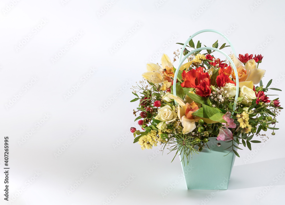 Delicate orchids in a gift box or basket on a light background. Space for text. Bouquet of orchids, roses and chrysanthemums. Festive postcard.