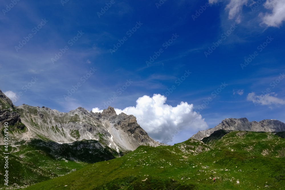 high rocky mountains with a green meadow and blue sky