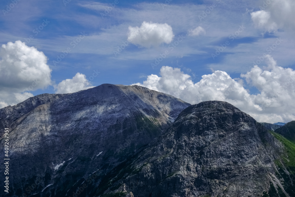 high steep mountains with white clouds on the blue sky