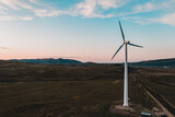 Wind turbine, alternative energy, wind energy, one windmill in a field in the mountains, top view of a wind turbine at sunset.