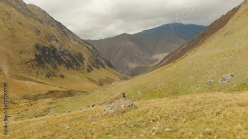 Aerail fly over Female backpacker woman standing on rock and admiring beautiful valley. KAzbegi hiking adventure photo