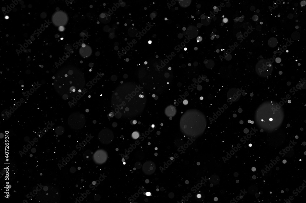 Obraz premium Bokeh of white snow on a black background. Snowfall - design element.
