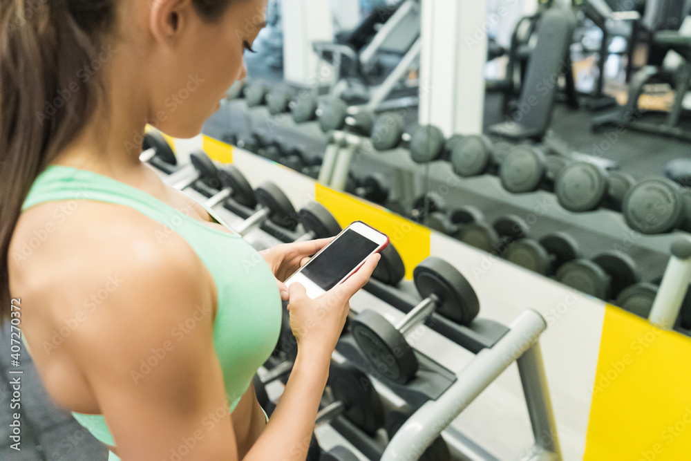 Fototapeta premium Sportswoman using mobile in gym