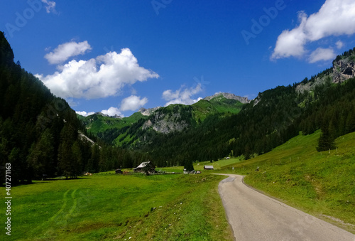 dirt road into a beautiful valley with green mountains and blue sky