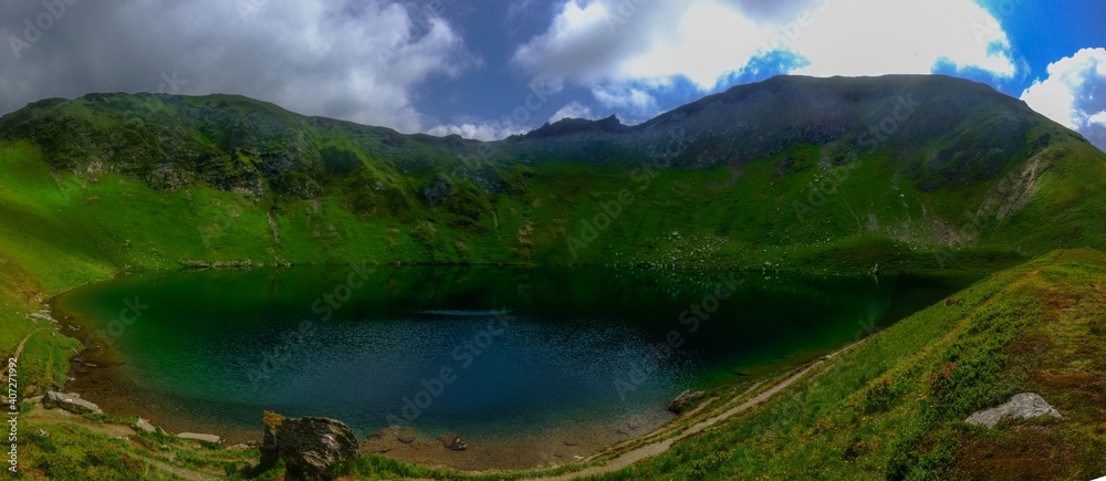 clear mountain lake in the middle of green mountains while hiking