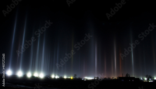 Night photo of the village, light rays from searchlights in the cold.