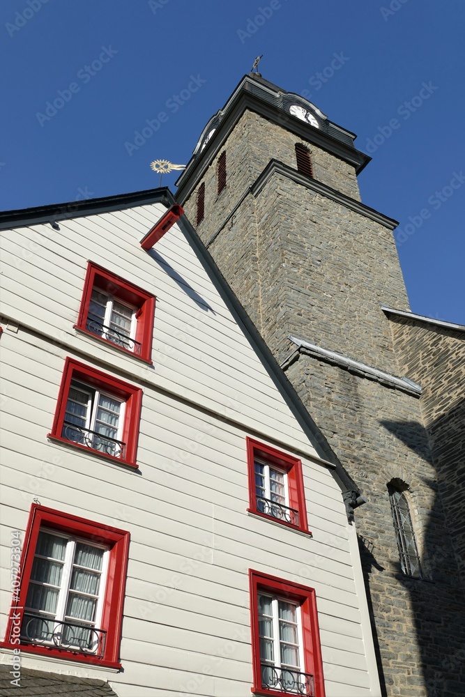 Emporragender Kirchturm Aukloster mit Hausfassade in Monschau / Eifel