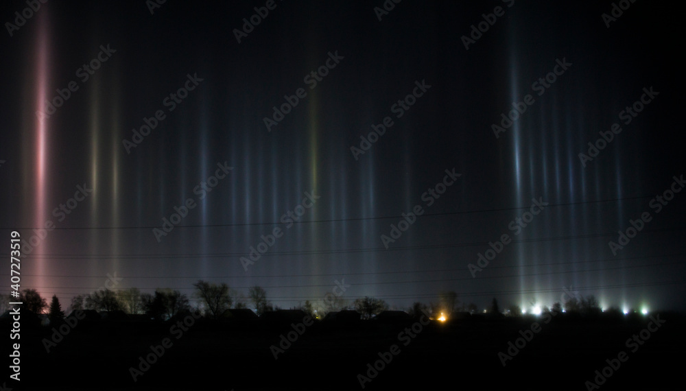 Night photo of the village, light rays from searchlights in the cold.