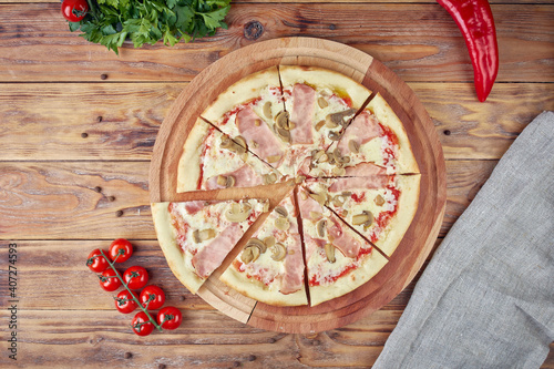 Pizza with meat, vegetables and mushrooms, wooden background