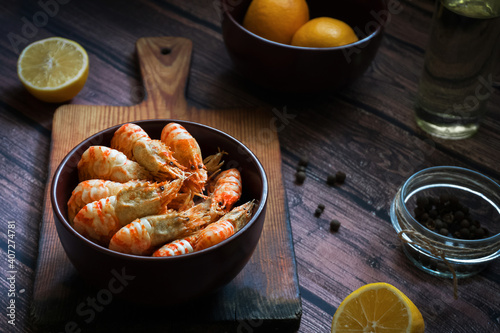 Greenland shrimp. Bowl with boiled shrimp, lemon and olive oil on a wooden background. Top view.