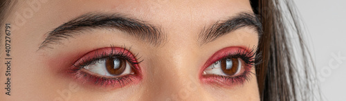 Macro shot of female eyes with red eyeshadow make-up. Close-up of woman eyelashes. Panoramic shot. High quality image. Panorama banner.