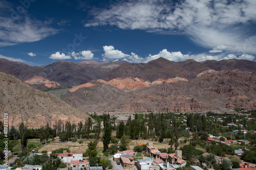 Tilcara village at the foot of the mountains. Panorama view of the colorful mountains and town buildings under a beautiful sky with clouds.