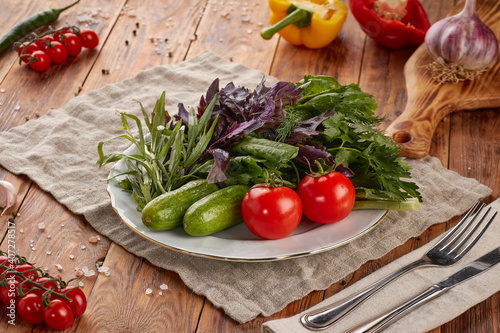 Plate of fresh vegetables and herbs on wooden background