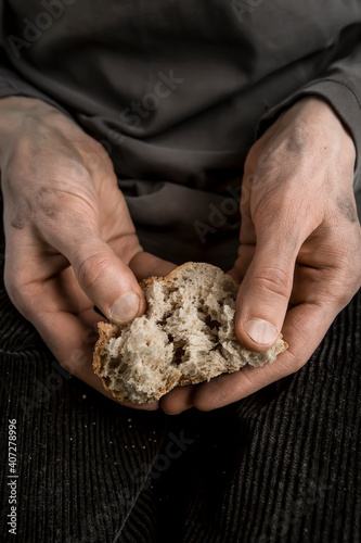 The poor man's hands are holding pieces of bread. Hunger and poverty concept.