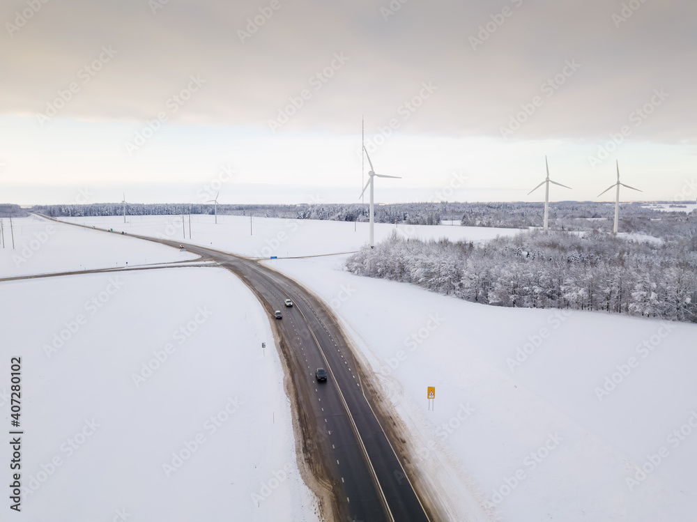 Drone view of the paved road and wind turbines on a winter day. Wind turbines for generating electricity using clean and renewable energy