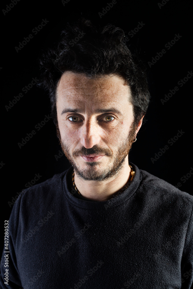 Corridor lighting setup portrait of an adult white man with rock hairstyle and beard looking attractive and serious to the camera. Black background portrait.