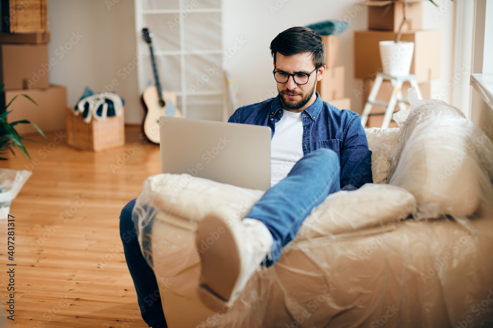 Mid adult man using laptop while relaxing at his new apartment. Mid adult man using laptop while relaxing at his new apartment.