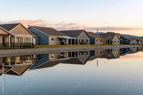 A row of similar homes in a waterfront subdivision reflect along a smooth lake in Post Falls, Idaho, USA. photo