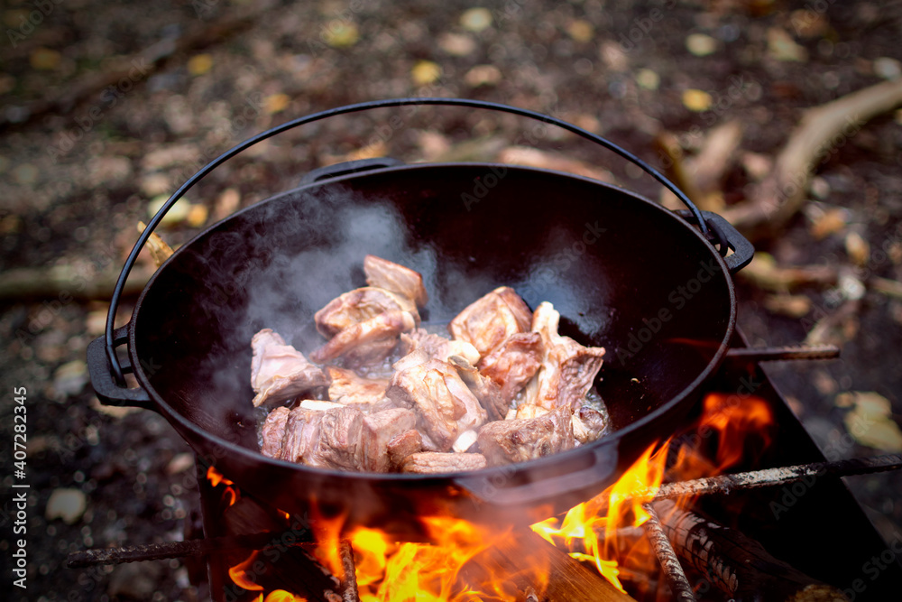 Cooking pilaf in Asian cauldron on the grill outside in forest. Selected focus. Cooking pilaf in Asian cauldron on the grill outside in forest. Selected focus.