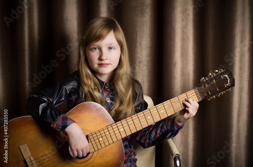 Little girl with a guitar on a brown background.