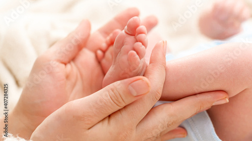 Closeup of woman gently stroking with hand tiny feet of her newborn baby son with perfect skin. Concept of family happiness and loving parents with little children © Кирилл Рыжов