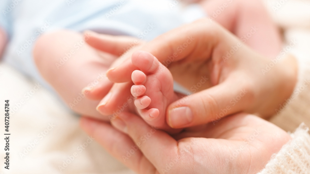Closeup image of mother massaging little feet of her newborn baby boy lying on bed Closeup image of mother massaging little feet of her newborn baby boy lying on bed