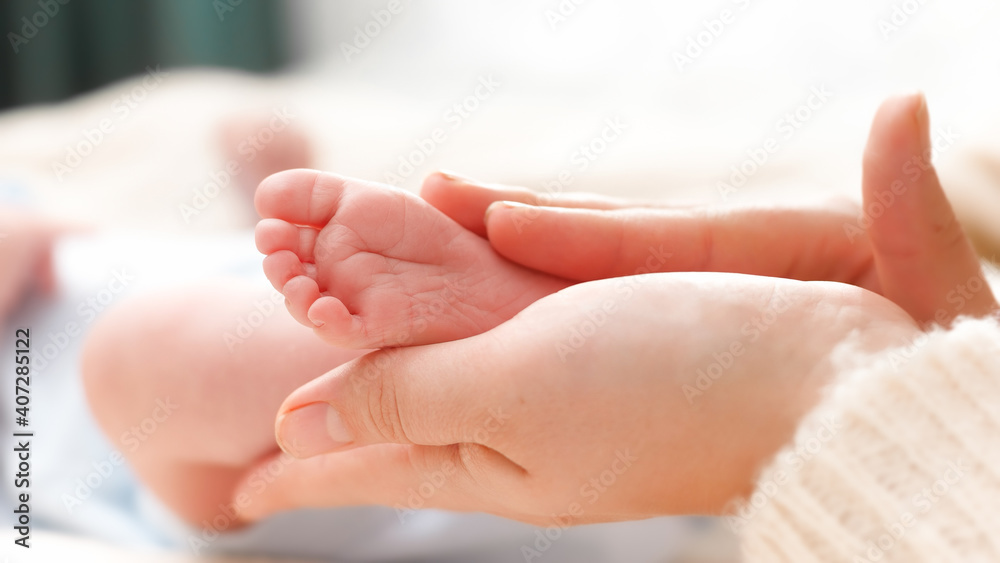 Tiny baby feet in female hands. Young mother gently touching and stroking her newborn baby legs. Concept of family happiness and loving parents with little children. Tiny baby feet in female hands. Young mother gently touching and stroking her newborn baby legs. Concept of family happiness and loving parents with little children.