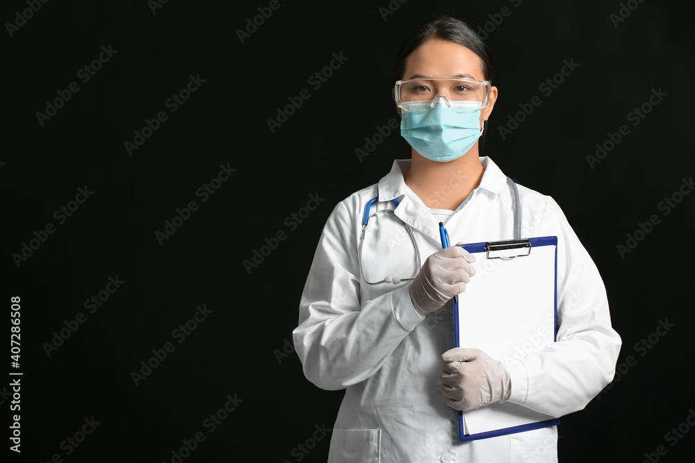 Portrait of female Asian doctor with clipboard on dark background Portrait of female Asian doctor with clipboard on dark background
