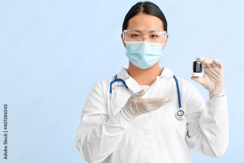 Portrait of female Asian doctor with pulse oxymeter on color background Portrait of female Asian doctor with pulse oxymeter on color background