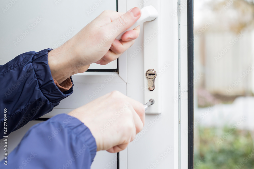 Handyman installing lock in plastic front door. Checking the door lock with a screwdriver for operability. Handyman installing lock in plastic front door. Checking the door lock with a screwdriver for operability.