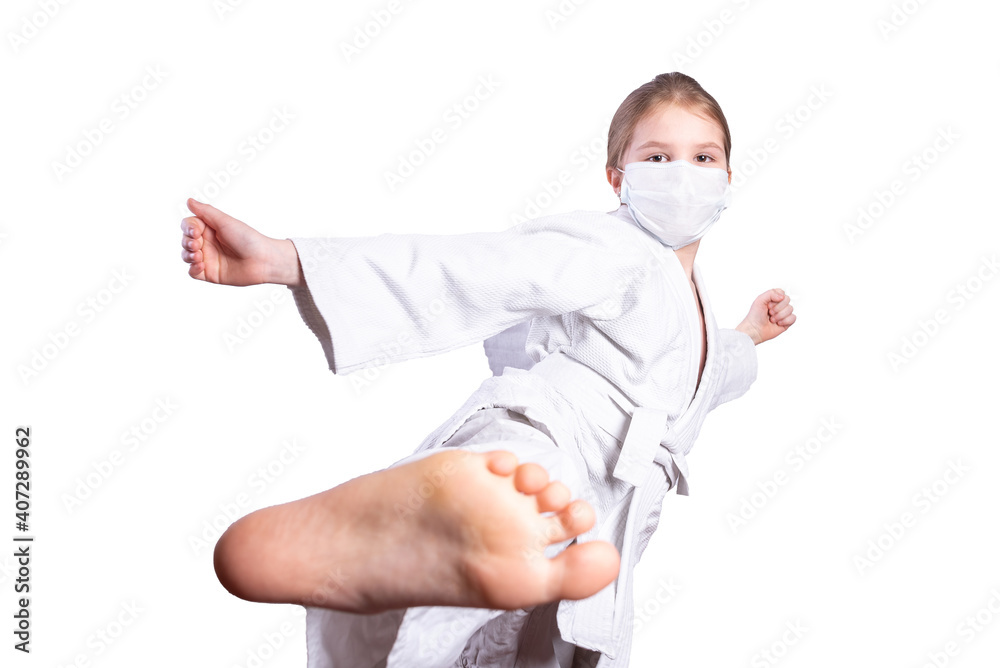 A girl in a judo kimono, and a medical mask. He kicks. Isolated on white background.