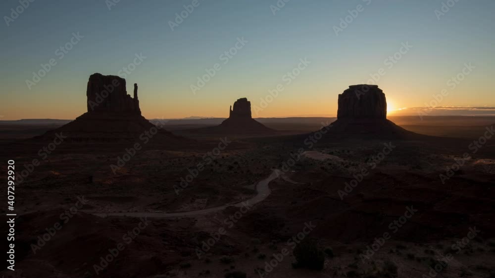 Time lapse sunrise in Monument Valley, Airzona. Beautiful orange morning sun light shining behind massive red cliff mountains. People driving in valley to enjoy nature. World famous background, USA 4K Time lapse sunrise in Monument Valley, Airzona. Beautiful orange morning sun light shining behind massive red cliff mountains. People driving in valley to enjoy nature. World famous background, USA 4K