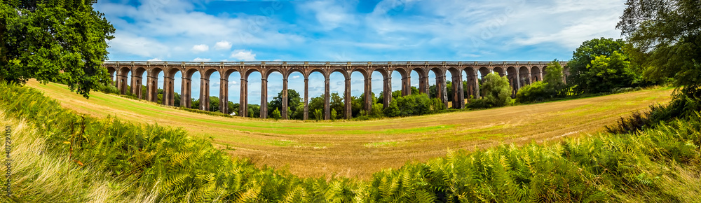 A wide-angle view over the hedgerows towards the Ouse Valley viaduct in Sussex, UK on a summers day A wide-angle view over the hedgerows towards the Ouse Valley viaduct in Sussex, UK on a summers day