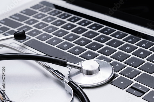 Computer repair, IT industry or modern medical service concept - black stainless stethoscope on a laptop keyboard in close-up