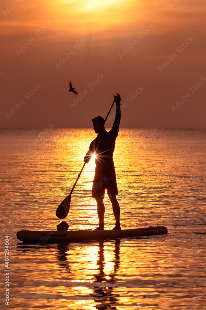 Standup Paddler im Sonnenaufgang 