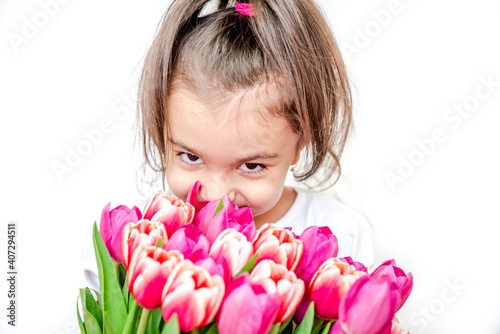 Portrait of a beautiful smiling little girl with spring tulips on a white background. International Women's Day. Girl 5 years old, Caucasian. Isolated.