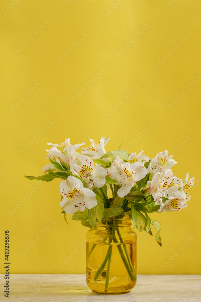 Florero amarillo con ramo de flores blancas sobre una mesa de mármol y fondo de color amarillo. concepto decoración de interiores