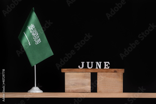Wooden calendar of June with Saudi Arabia flag on black background. Dates of Saudi Arabia in June