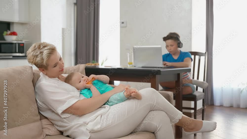 Mother playing with one son while another using laptop Mother playing with one son while another using laptop