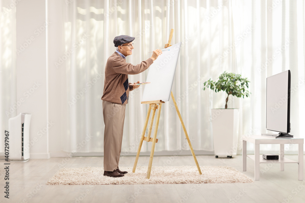 Elderly male artist painting on a canvas at home