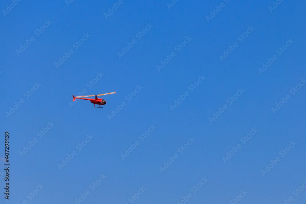 Flying orange helicopter in blue sky Flying orange helicopter in blue sky