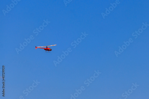 Flying orange helicopter in blue sky