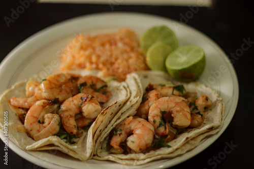 Agillo shrimp tacos with red rice soup and lemons. photo