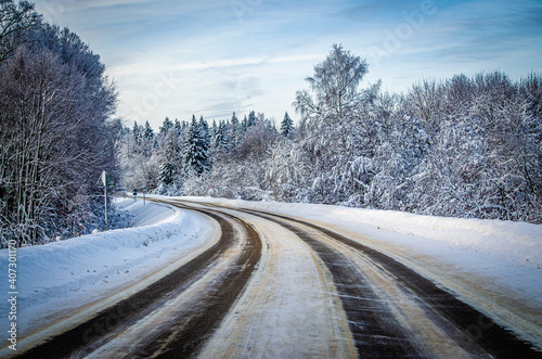 Winter road surrounded by a snowy winter forest in the Moscow region. The nature of Russia.