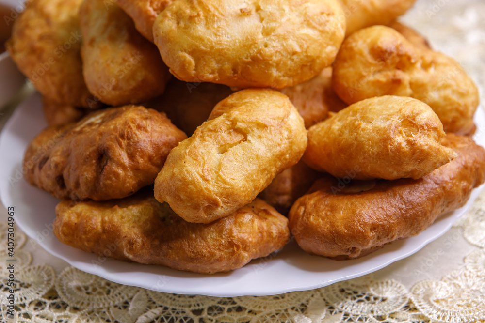 Freshly baked delicious pies with a brown crispy crust lie on a white ceramic plate. Close-up. Freshly baked delicious pies with a brown crispy crust lie on a white ceramic plate. Close-up.