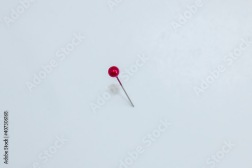 Rote Stecknadel steckt im Untergrund und wirft einen Schatten.
