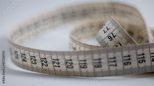 Close up of a two meter long measuring tape. Background is blurry.